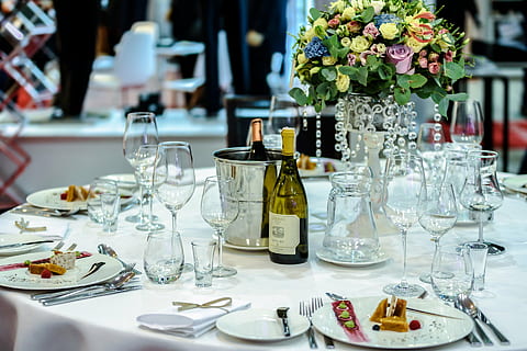 clear wine glasses, plates, and liquor bottles on table with flower centerpiece HD wallpaper
