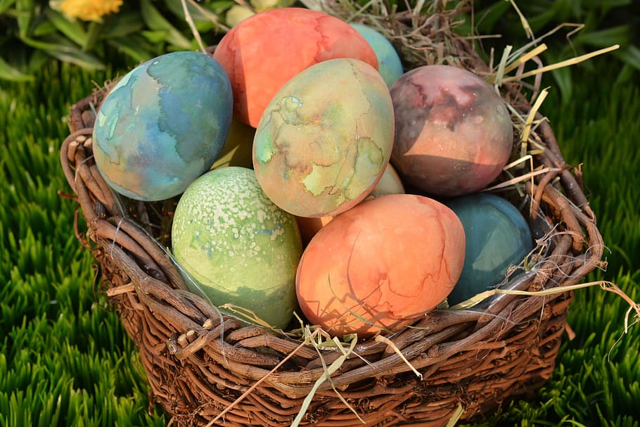 assorted-color Easter eggs on brown wicker basket, easter nest