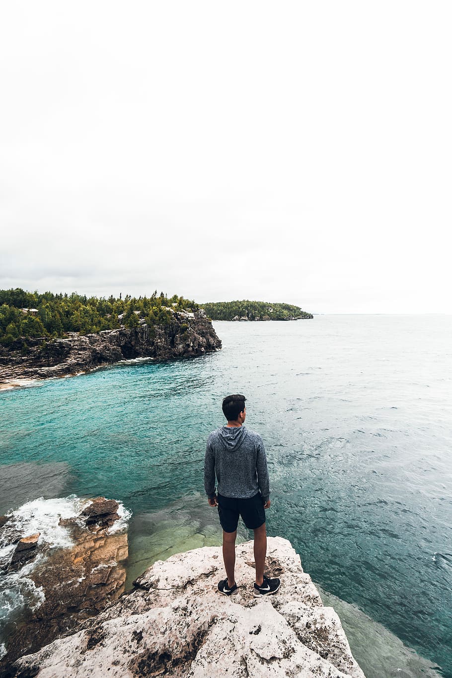 man standing on white and brown rock seeing horizon during daytime, man standing on rock near water, HD wallpaper