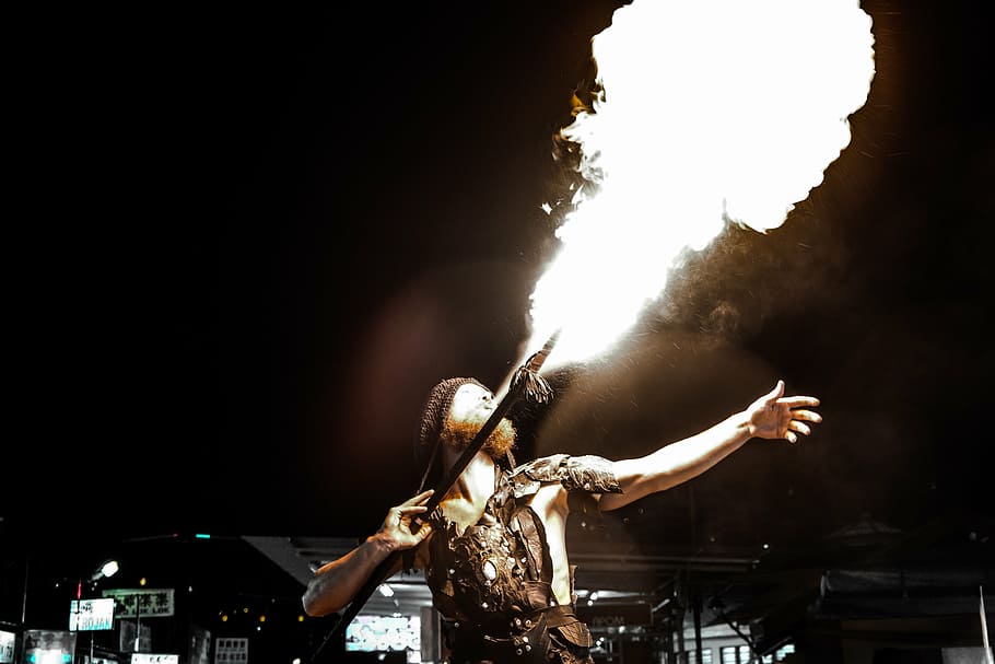 man holding stick while blowing fire during nighttime, playing HD wallpaper