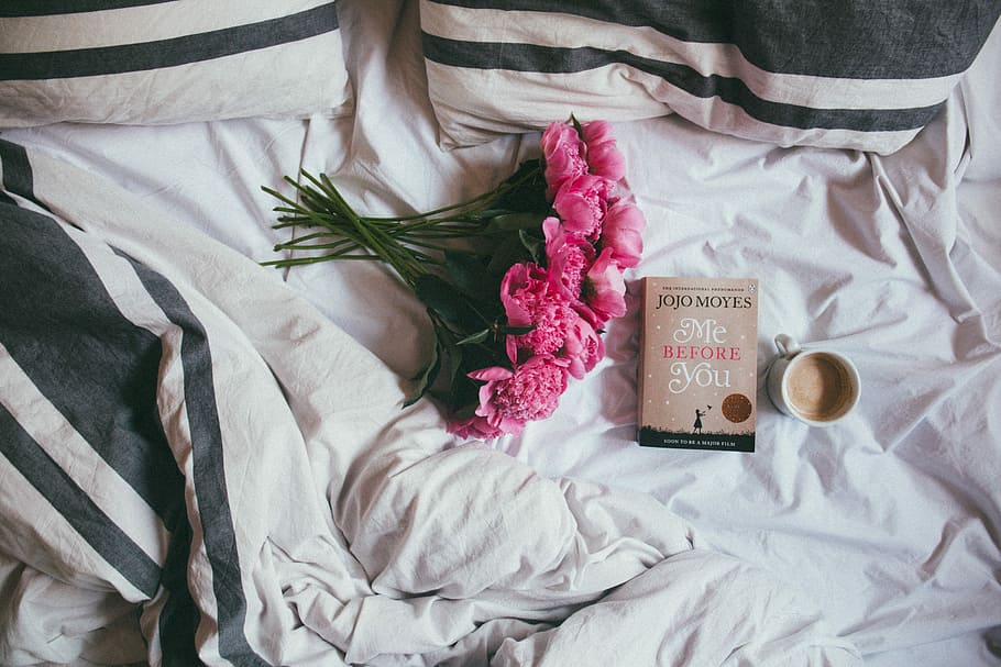 bouquet of pink flowers on top of bed, pink rose flower bouquet beside Me Before You by Jojo Moyes book and white ceramic mug on white and black bedspread HD wallpaper
