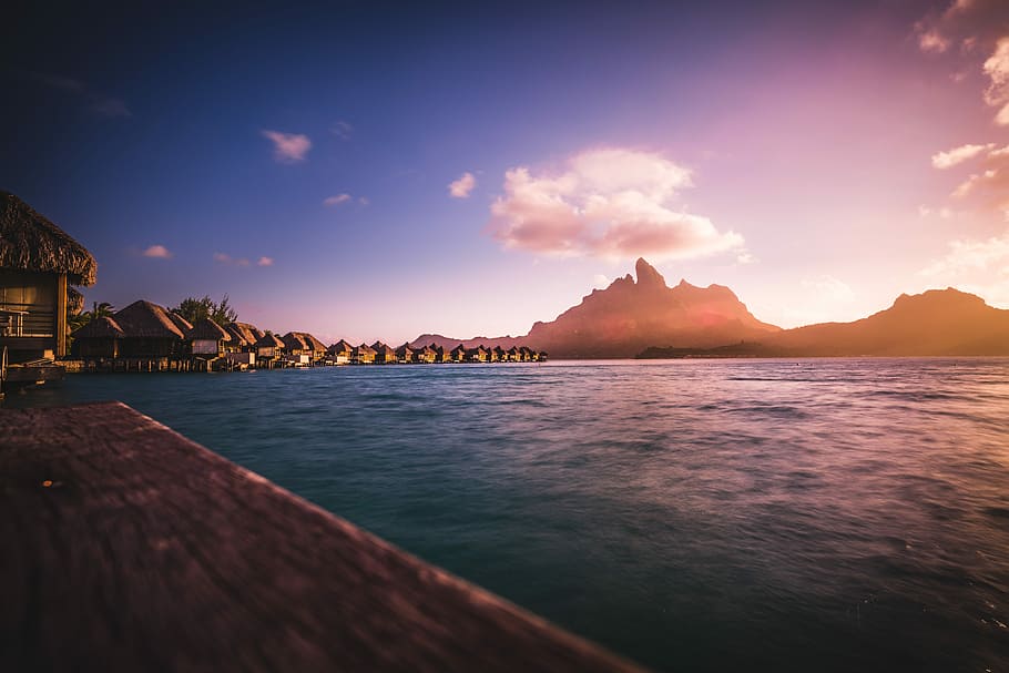 huts neat water and mountain, village near sea during golden hour HD wallpaper