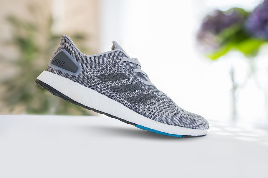 selective focus photography of unpaired grey and white adidas shoe on white surface