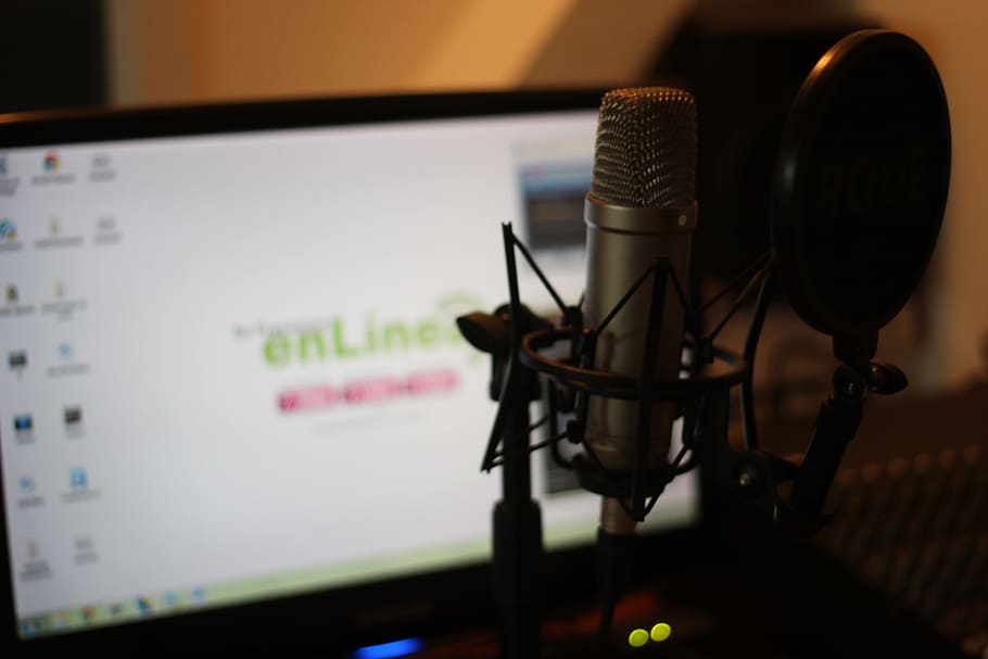 selective focus photography of gray condenser microphone with filter in front of flat screen computer monitor