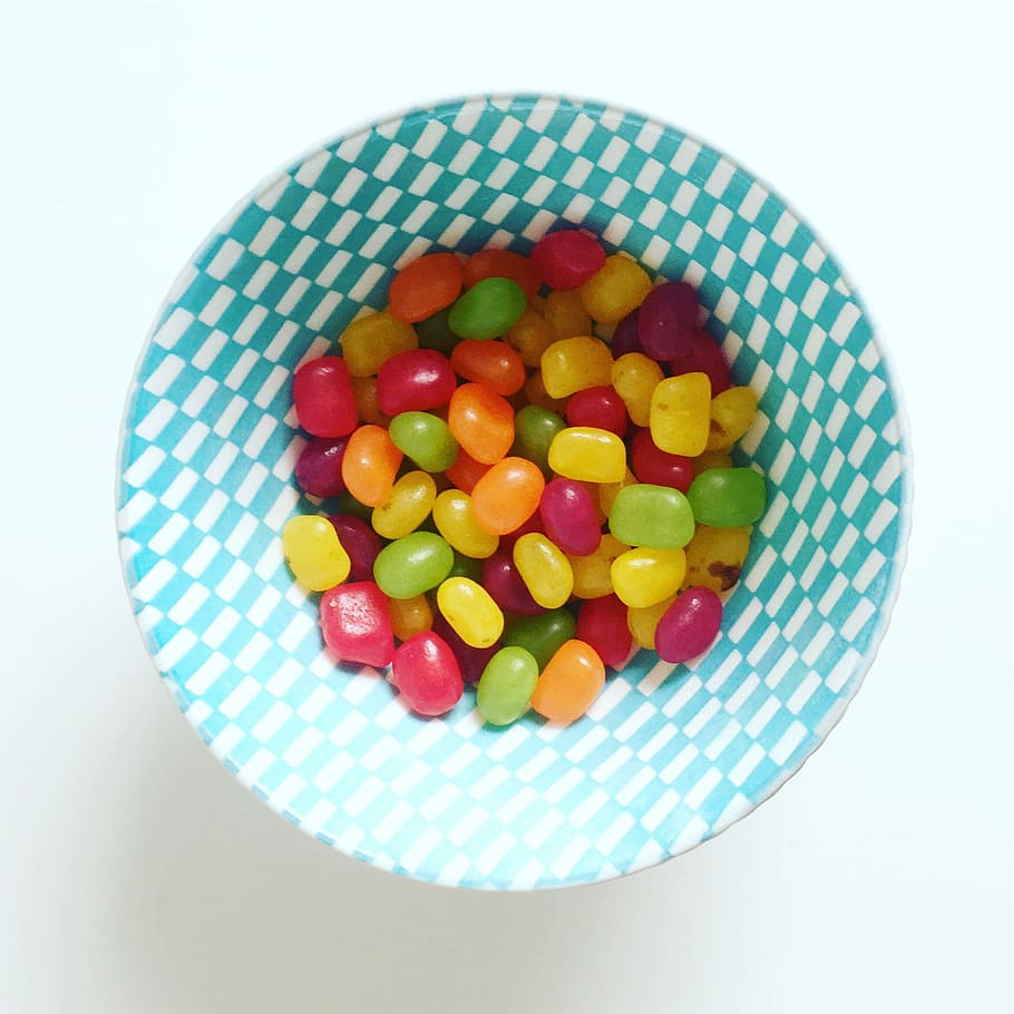 yellow, red, and green candies on round white and green checkered bowl