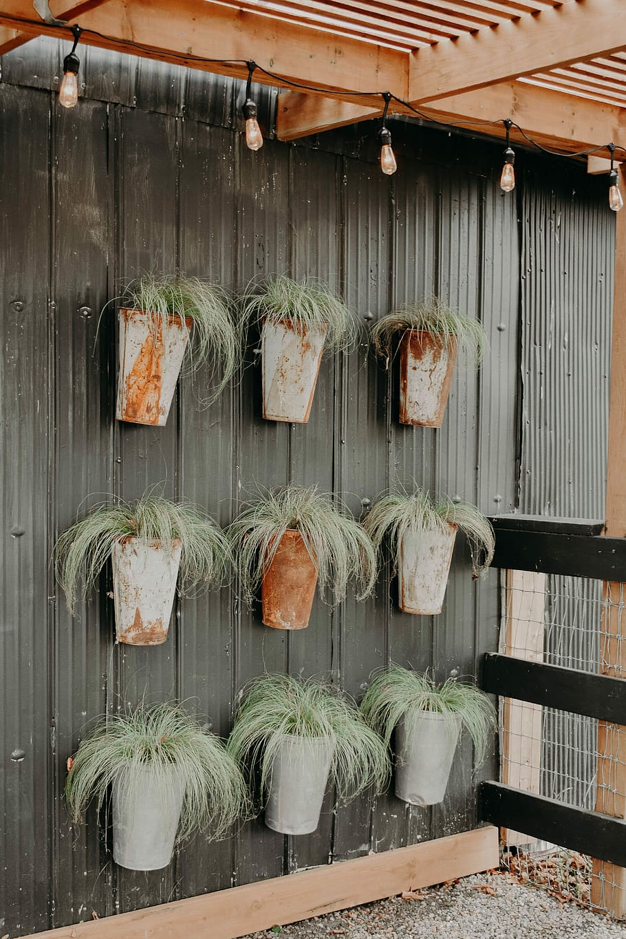 nine gray pots, green potted plants hanging on wall, fence, garden