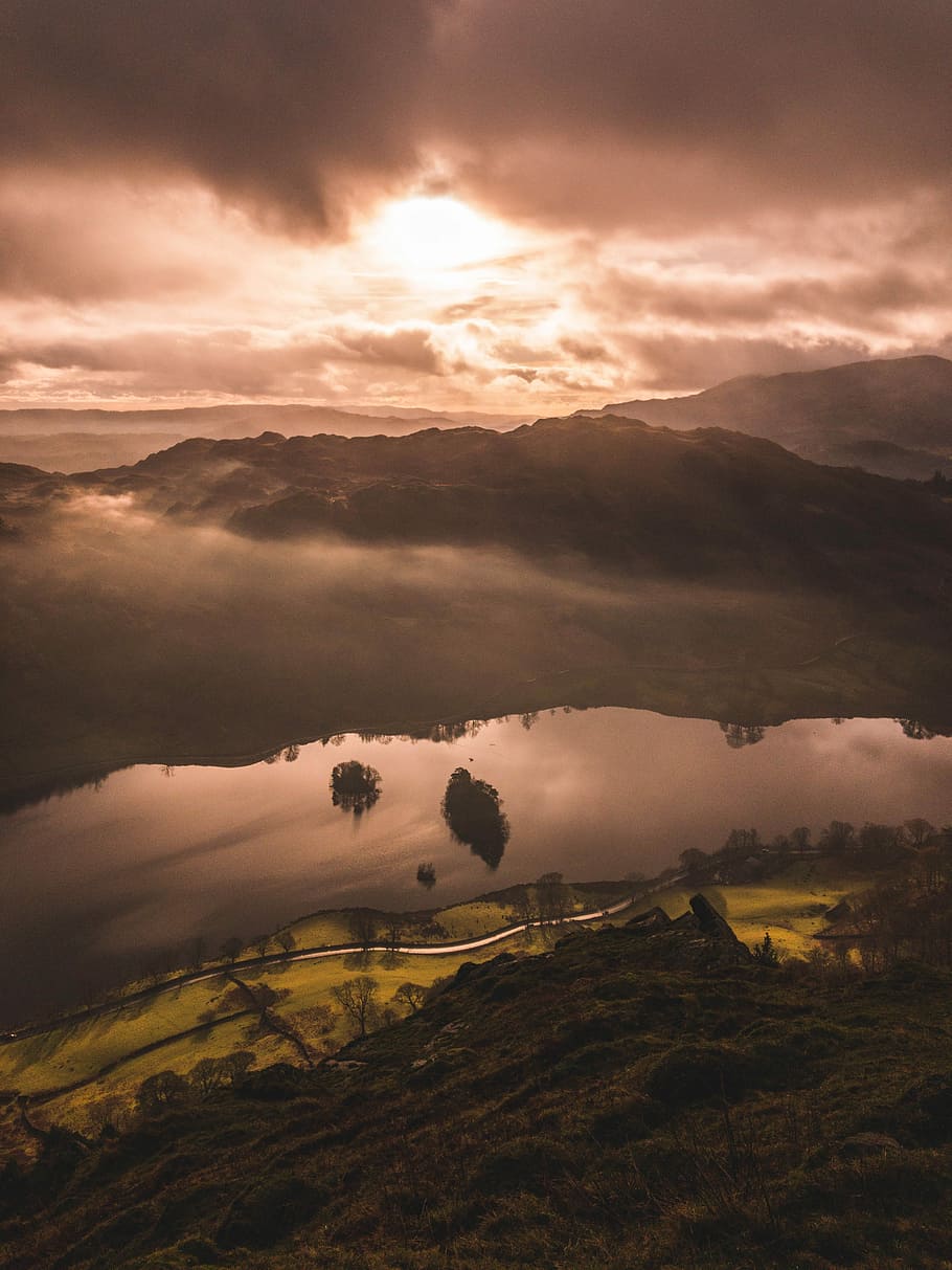mountain and body of water under brown skies, portrait photography of mountain and body of water during daytime HD wallpaper