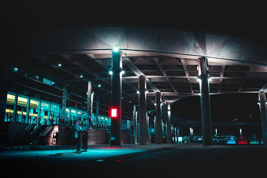 vehicle station with turned on light fixtures at night, white building during night time
