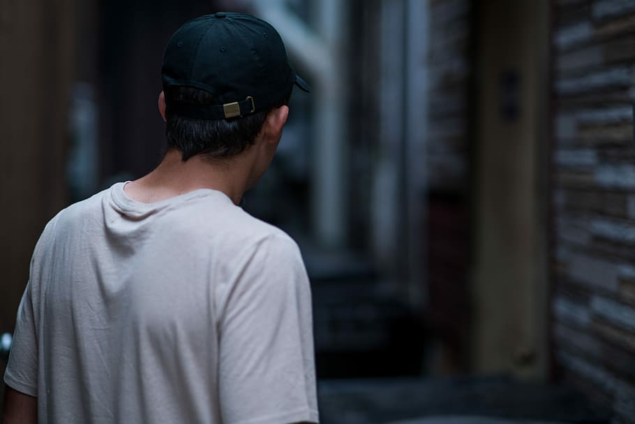 photo of man wearing white crew-neck T-shirt and black cap, man standing at the alley HD wallpaper