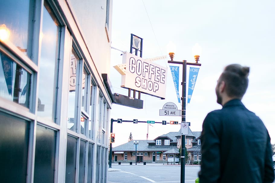 man in black dress shirt standing outside coffee shop during daytime HD wallpaper