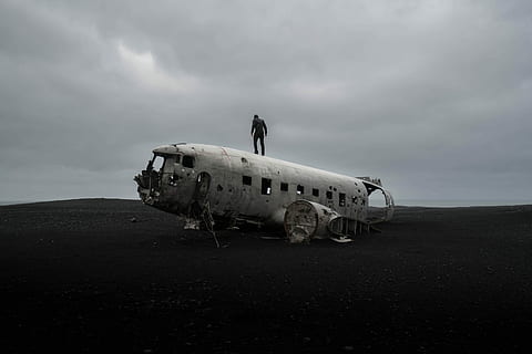 person standing on wrecked airplane under gloomy sky, silhouette of man standing on abandoned plane during daytime HD wallpaper