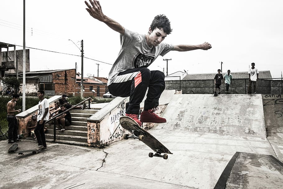 boy playing skateboard doing ollie, man in gray, crew-neck, t-shirt