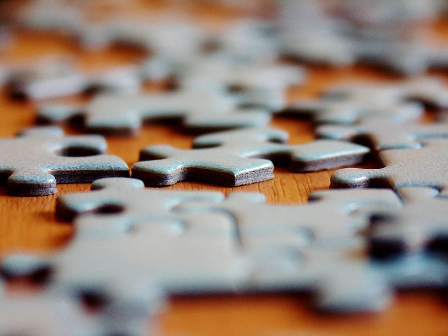 close-up photography of gray puzzles on brown surface, fit, puzzle pieces