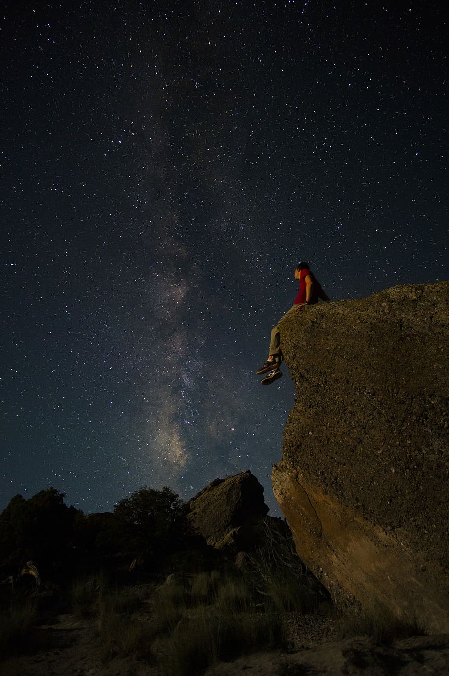 Hd Wallpaper Person Sitting On Edge Of Large Rock Under Starry Night Sky Man In Red T Shirt Sitting On Boulder Looking At The Sky Full Of Stars Wallpaper Flare