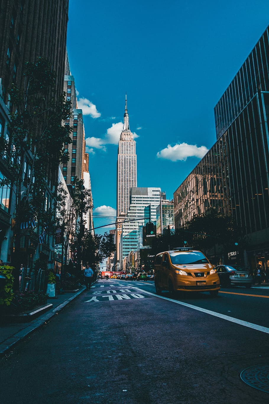 photo of Empire State Building in New York city, grey concrete buildings near vehicles under cloudy blue sky HD wallpaper