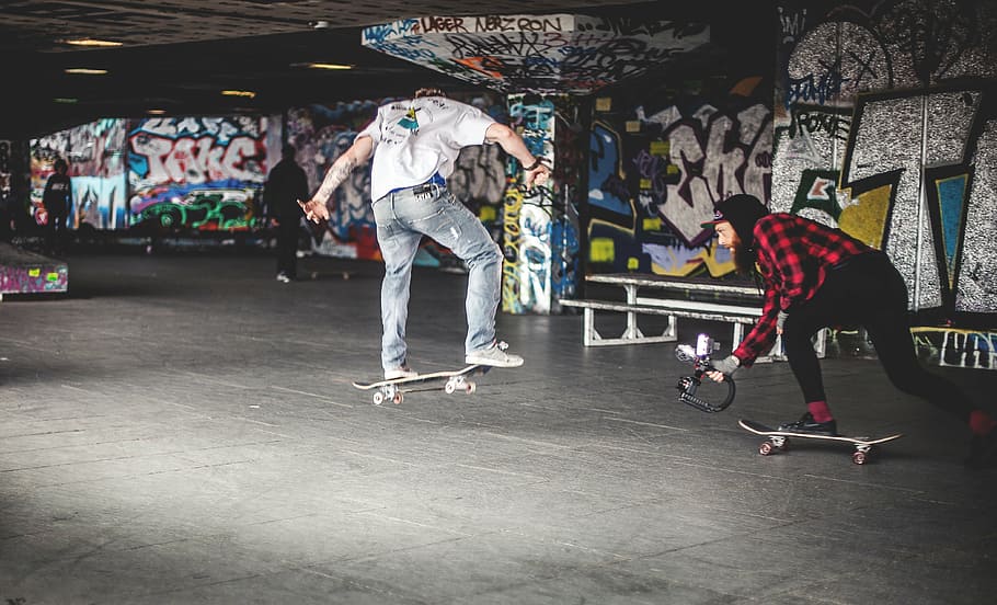 man wearing white shirt and jeans doing skateboard tricks, skateboarding