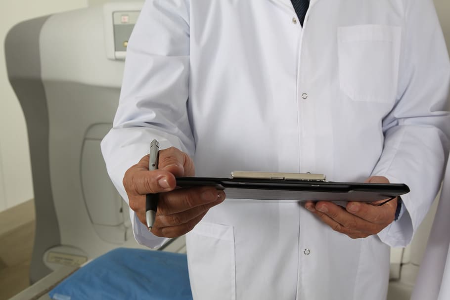 man wearing white coat holding black clipboard and pen, doctor