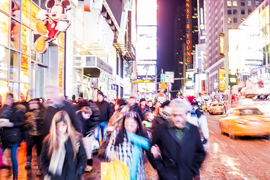 people walking between concrete buildings during nighttime HD wallpaper