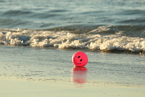 red smiley emoji ball on seashore, beach, happy, ocean, pink HD wallpaper