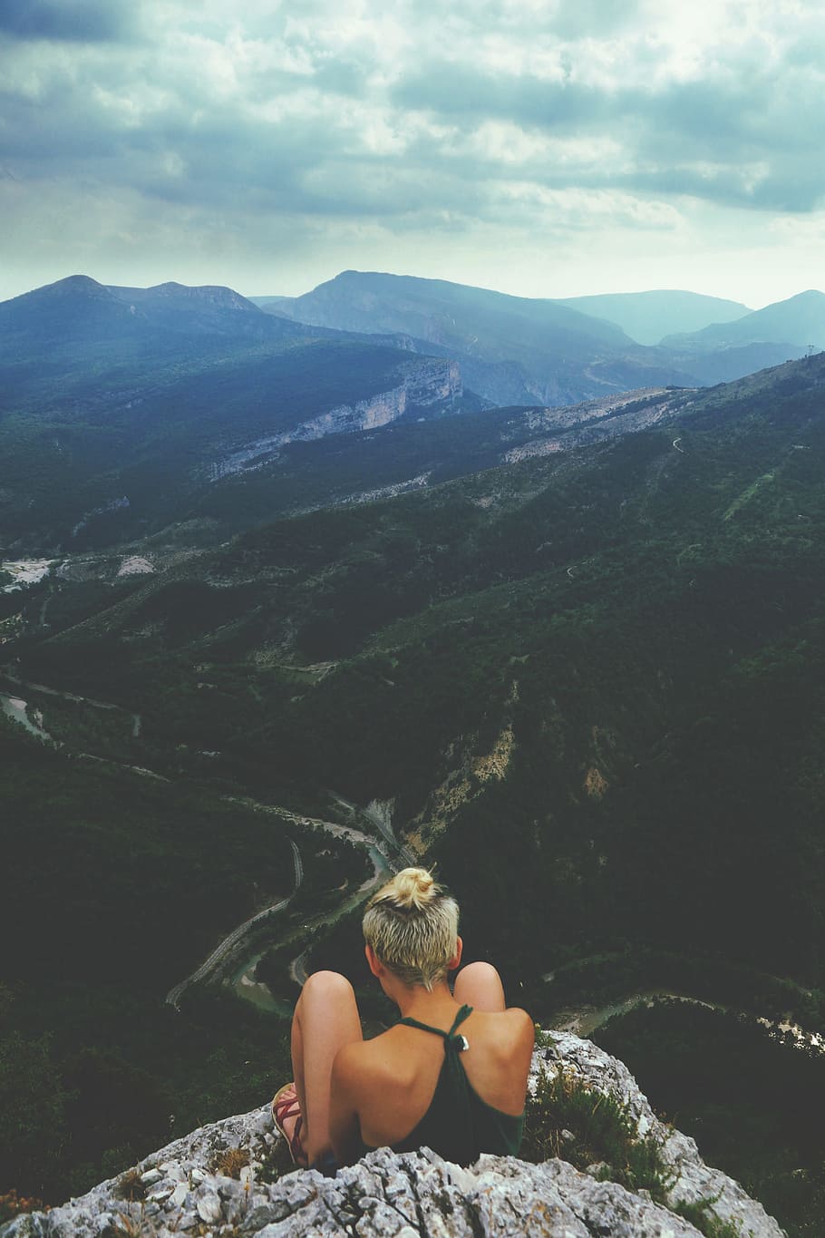 woman sitting next to cliff during daytime, woman sitting on peak of a mountain with mountain view HD wallpaper
