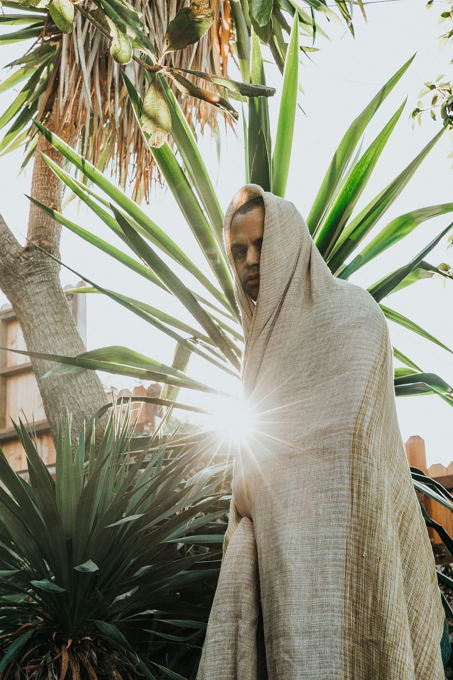 man in white top standing near plant, man wearing beige robe near palm tree HD wallpaper
