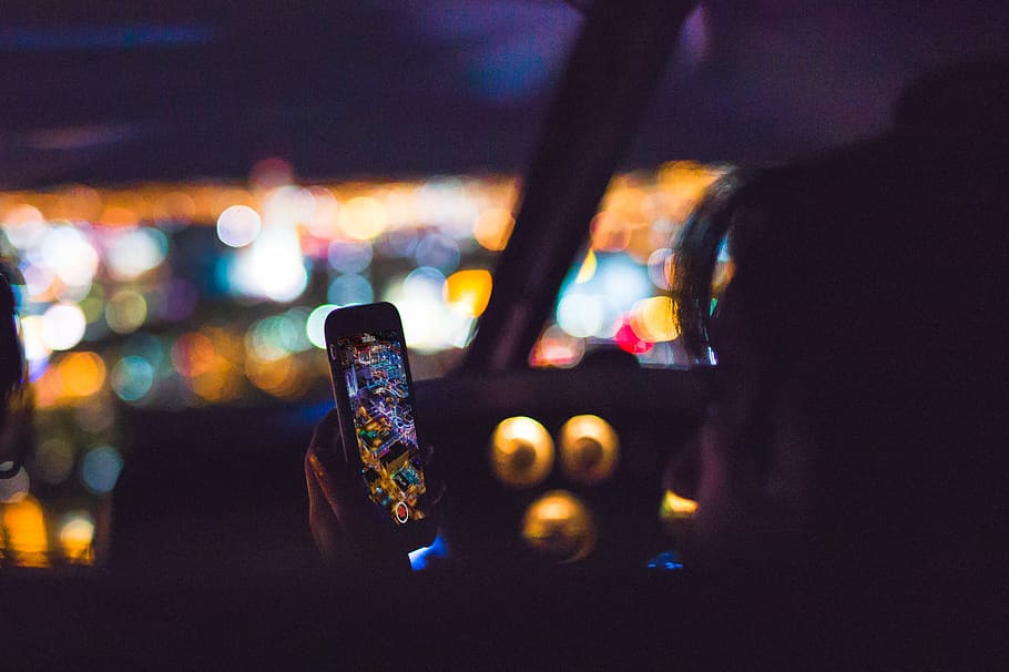 person using Android smartphone inside car, bokeh photography of person sitting on vehicle passenger seat holding turned on smartphone, HD wallpaper