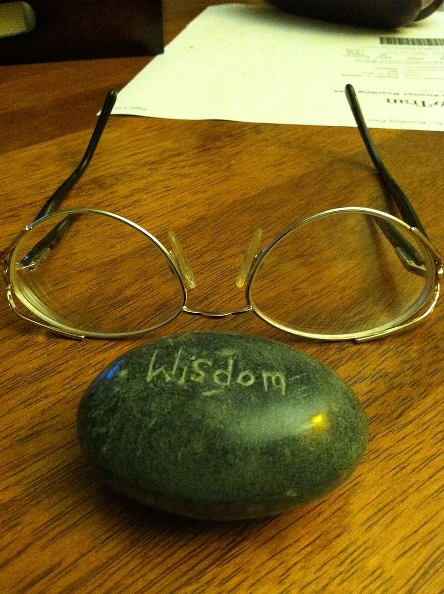 brass frame eyeglasses in front of stone with Wisdom text, working HD wallpaper