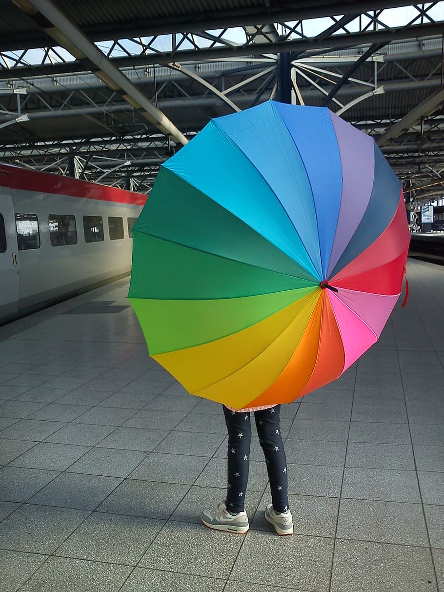 person standing while holding rainbow umbrella, train, station HD wallpaper