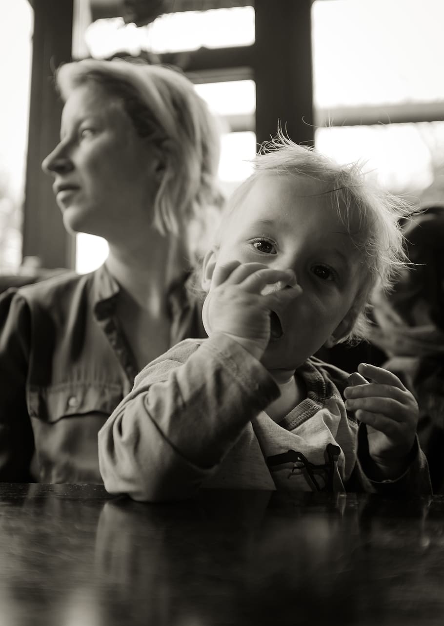 grayscale photography of child sitting on lap of her mother in front of the table, HD wallpaper