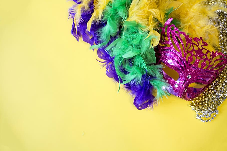 multicolored party mask on yellow surface, mardi gras, holiday