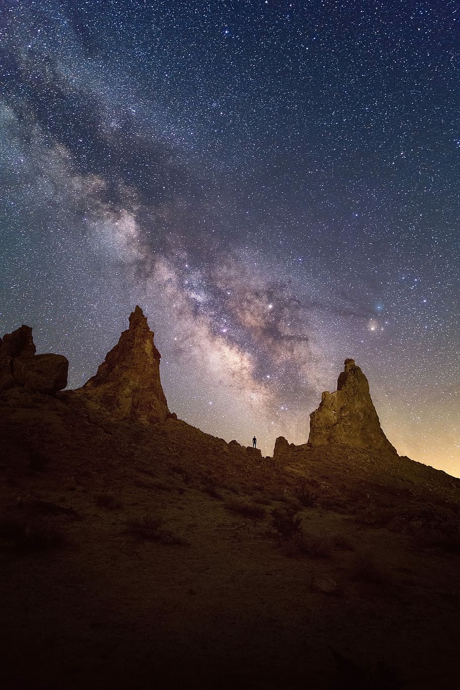 person standing on rock formation, landscape photography of two mountain rock formation with ocean of stars as background HD wallpaper