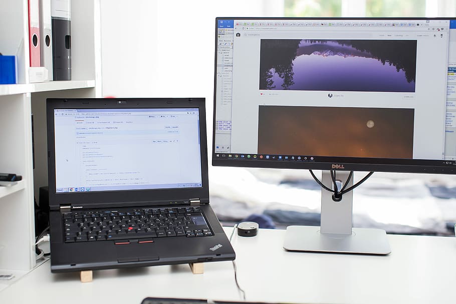 A laptop sitting next to a computer monitor., black Lenovo laptop beside monitor HD wallpaper