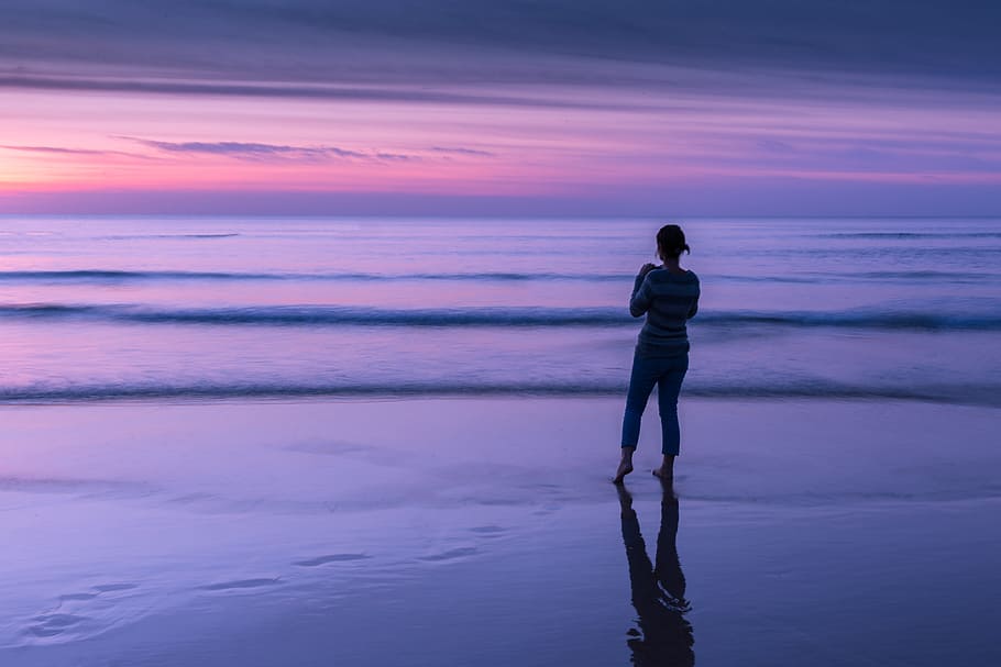 A woman looks out to sea at sunset on a beach in Cornwall, England. This image was captured using a Canon 6D DSLR HD wallpaper