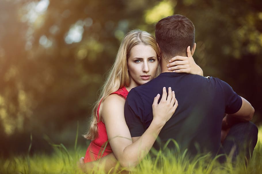 man and woman both sits on green grass field at daytime, romantic
