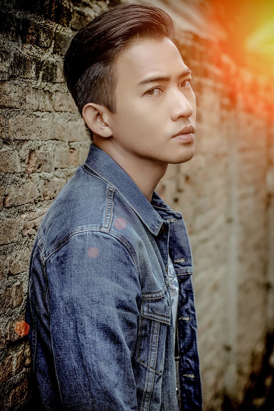 man wearing blue denim button-up jacket beside brown brick wall HD wallpaper
