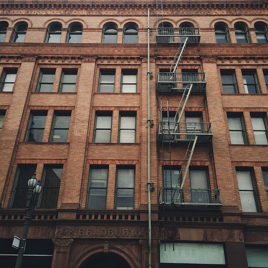 black exit ladder in front of concrete building, photography of brown concrete building with emergency stairs at daytime HD wallpaper