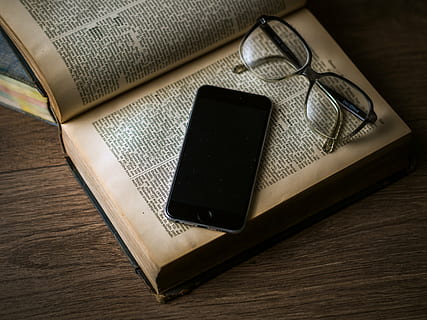 flat lay photography of space gray iPhone 6 on top of hardbound book beside black framed eyeglasses HD wallpaper