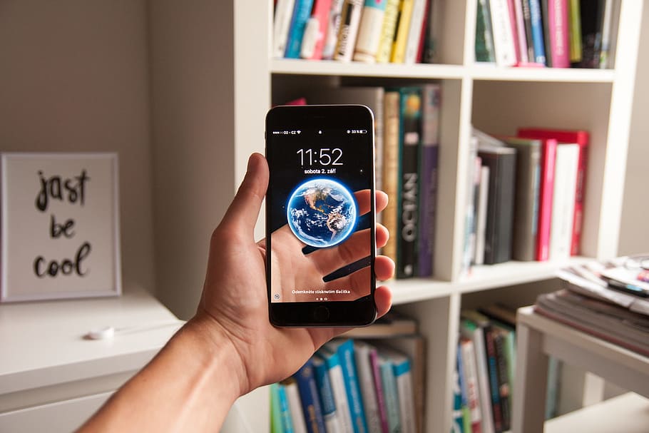 hand, earth, apple, iphone, bookcase, books, illusion, mobile phone HD wallpaper