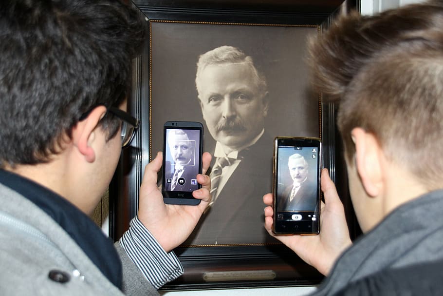 two men taking photo of portrait poster, smartphone, mobile phone