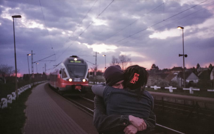two persons hugging each other on train station platform, together