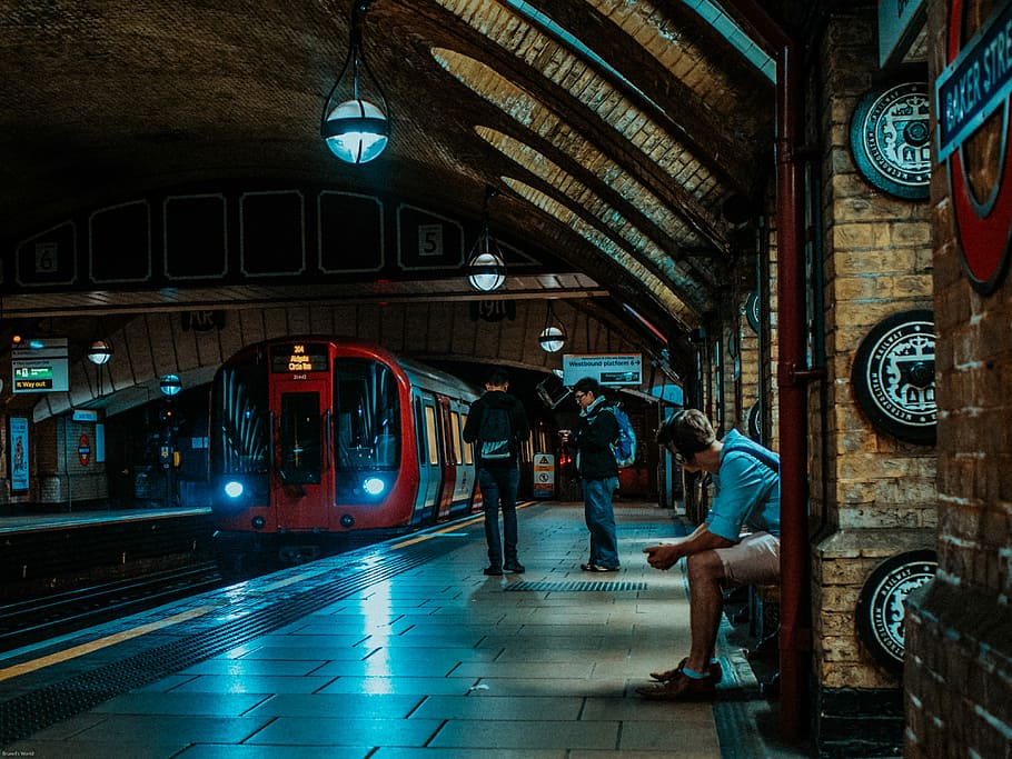 three persons waiting for train, two men waiting near train queue