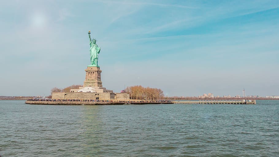 Statue Of Liberty on island surrounded by water, Statue of Liberty, New York taken under white clouds at daytime, HD wallpaper