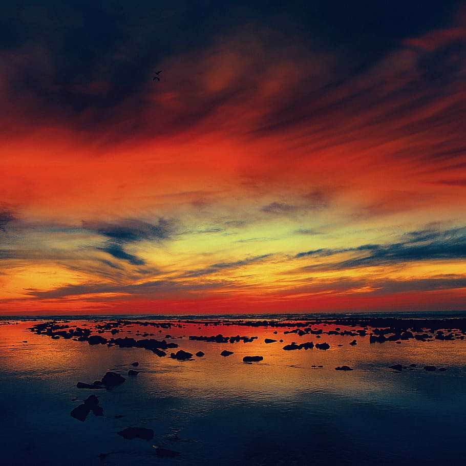 silhouette of rocks on body of water under red and blue clouds, golden hour photography HD wallpaper