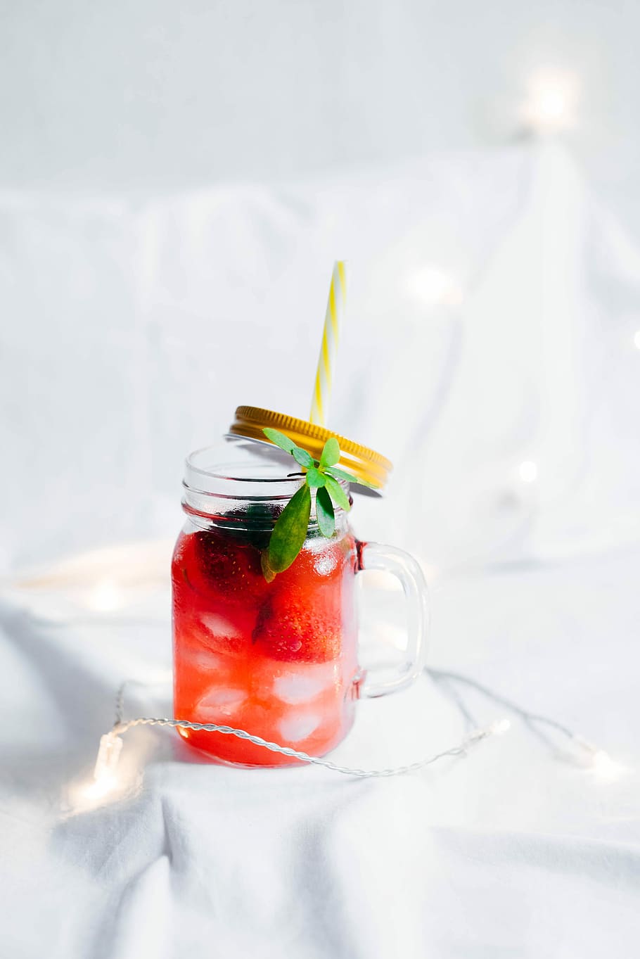 clear glass mason mug with strawberry drink on white textile surrounded by string light, clear glass mason jar on white textile HD wallpaper