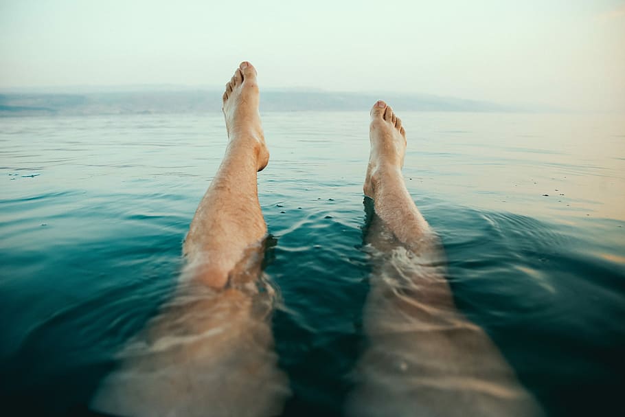 person's legs on water, person's feet above water at daytime