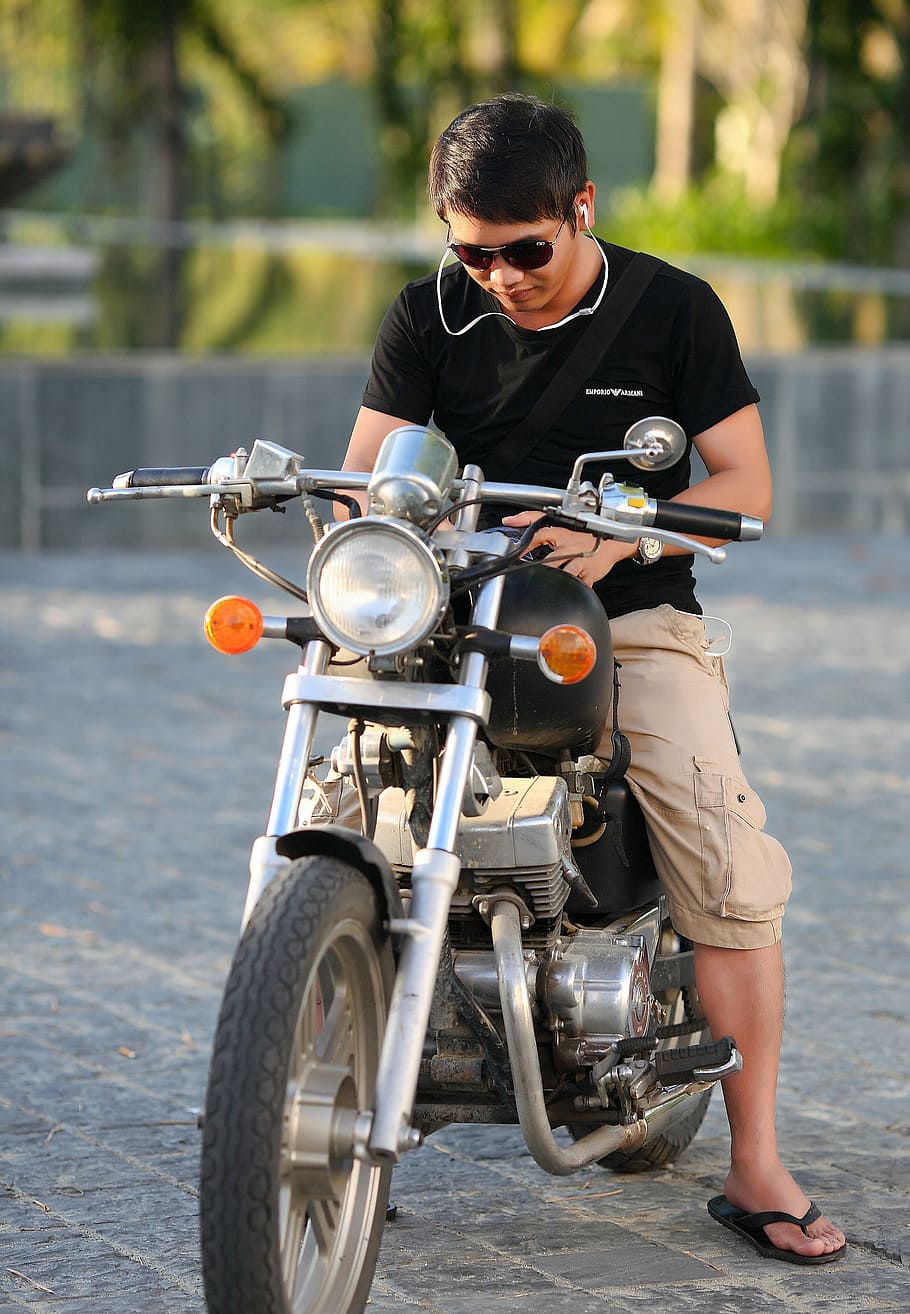 man wearing black T-shirt and khaki cargo shorts riding on motorcycle