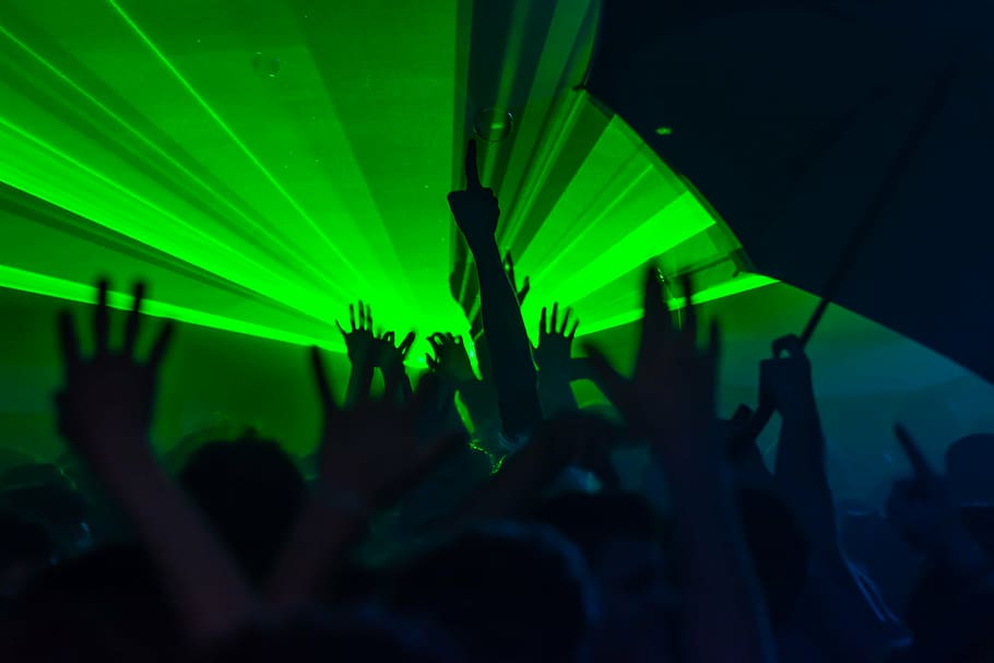 silhouette photography of people raising hands with green light