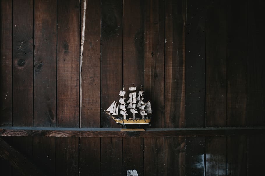 black, brown, and white galleon ship scale model on brown wooden shelf, brown and white galleon ship miniature