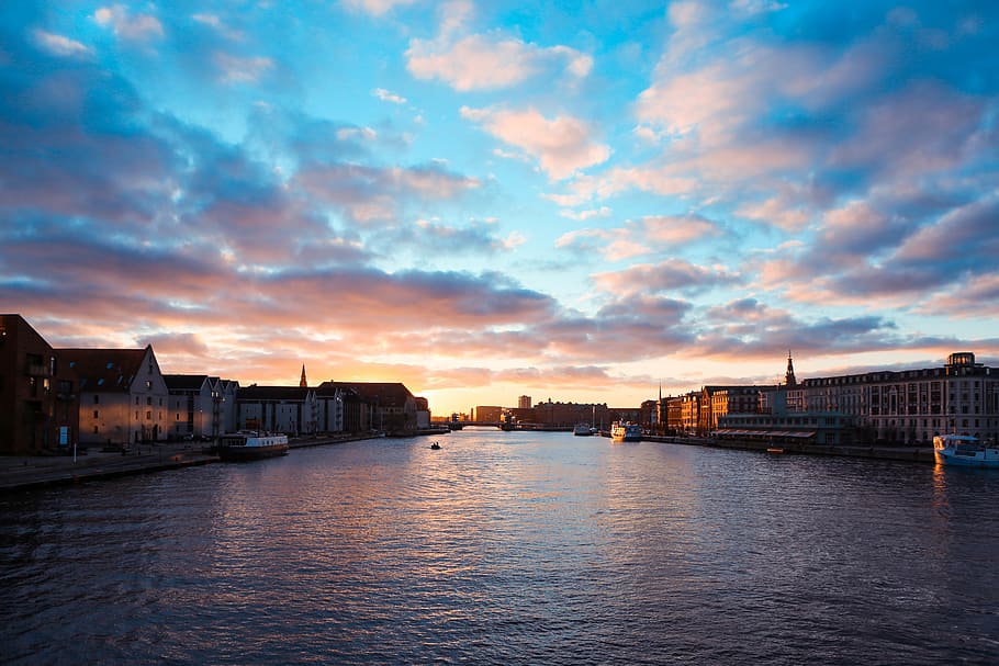 brown concrete building under white clouds during daytime, body of water near buildings during daytime HD wallpaper