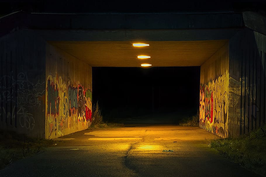 grey concrete tunnel turned on light with wall graffiti at nightie
